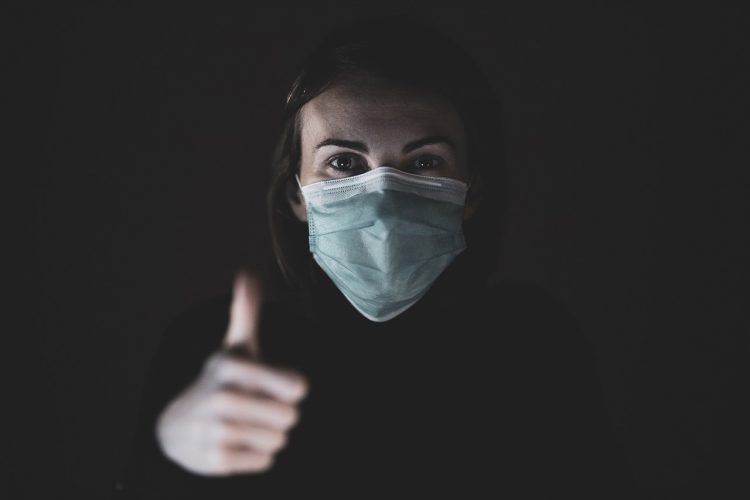 Enfermera con máscara debido a Covid-19, espresando esperanza.