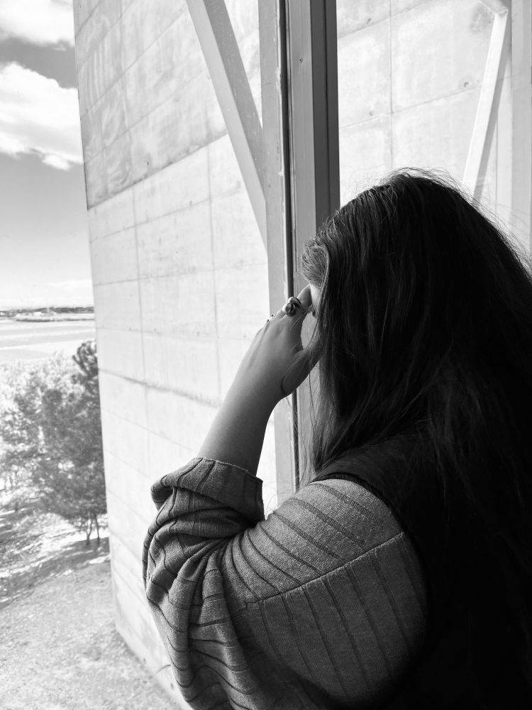 En la imagen se observa a una joven mirando por una ventana. mostrando de manera visual os pensamientos negativos de la misma ante un problema de salud mental. Algo que cada vez implica más a los adolescentes en España.