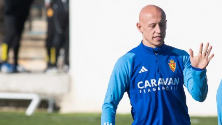 Un jugador de fútbol saluda a alguien con la mano izquierda durante una sesión de entrenamiento.